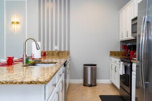 A modern kitchen with granite countertops, stainless steel appliances, and a trash can.