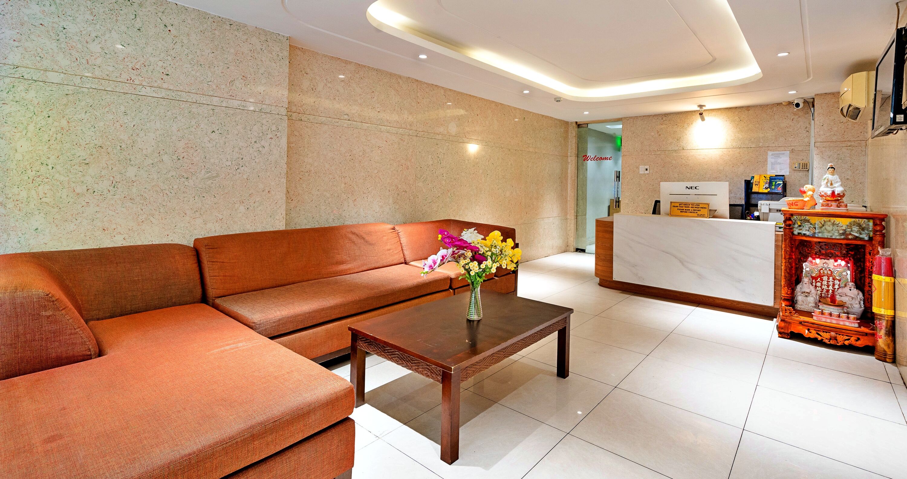 Un moderno vestíbulo de hotel con un sofá de cuero, una mesa de centro de madera y un mostrador de recepción.