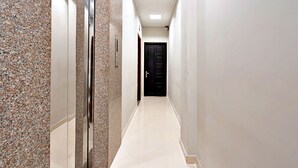 A narrow hallway with a marble wall on one side and a plain wall on the other, leading to a black door at the end. - Nicecy Daily - Bui Vien Walking Street (Ho Chi Minh City)
