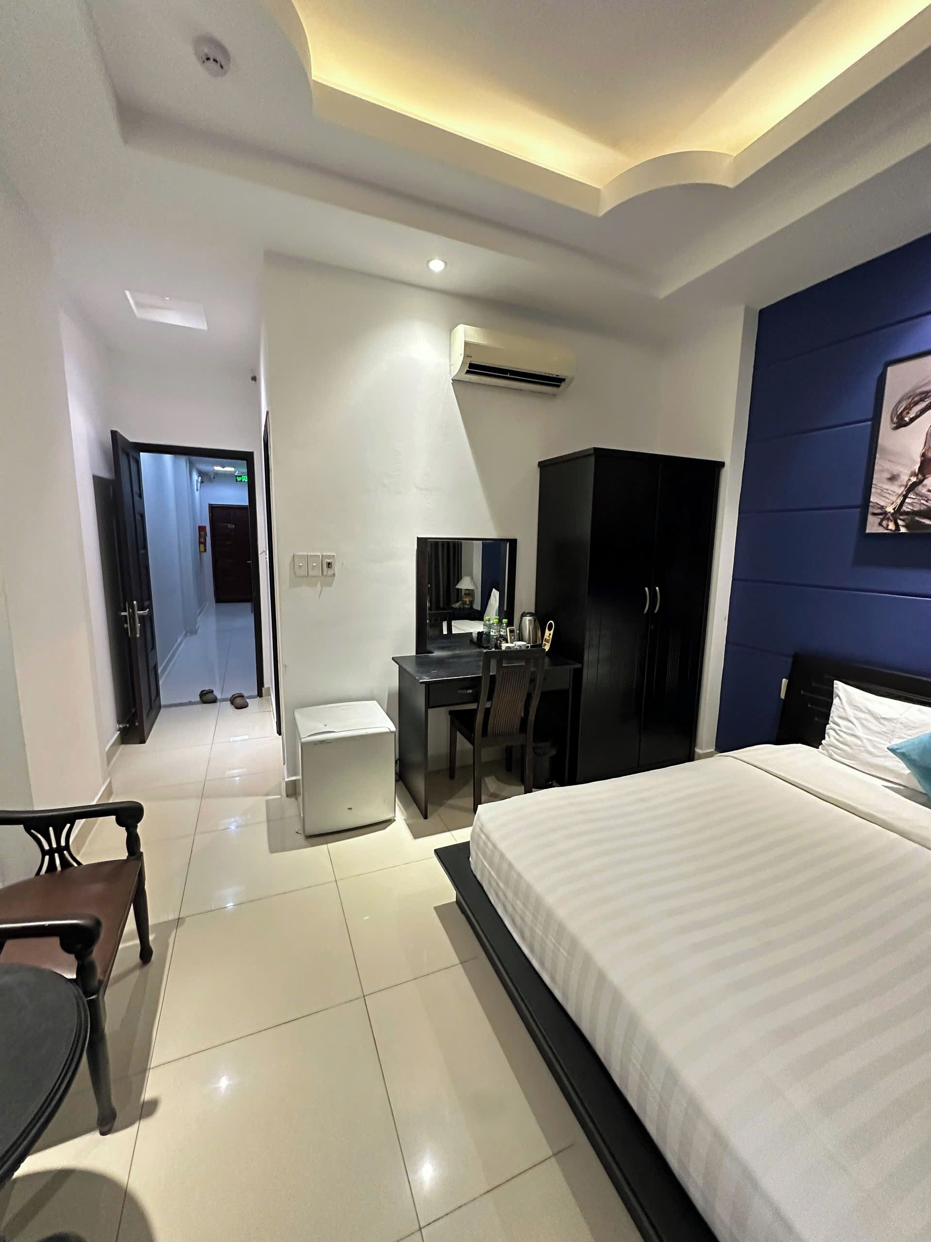 Una habitación de hotel moderna con una cama grande, un escritorio con una silla, un armario y un equipo de aire acondicionado en la pared.