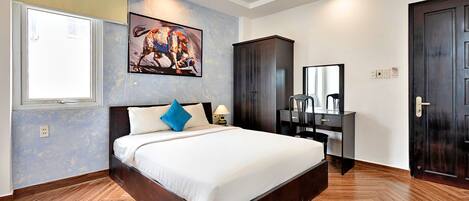 Une chambre d’hôtel avec un grand lit, un bureau avec une chaise, une armoire et un miroir.