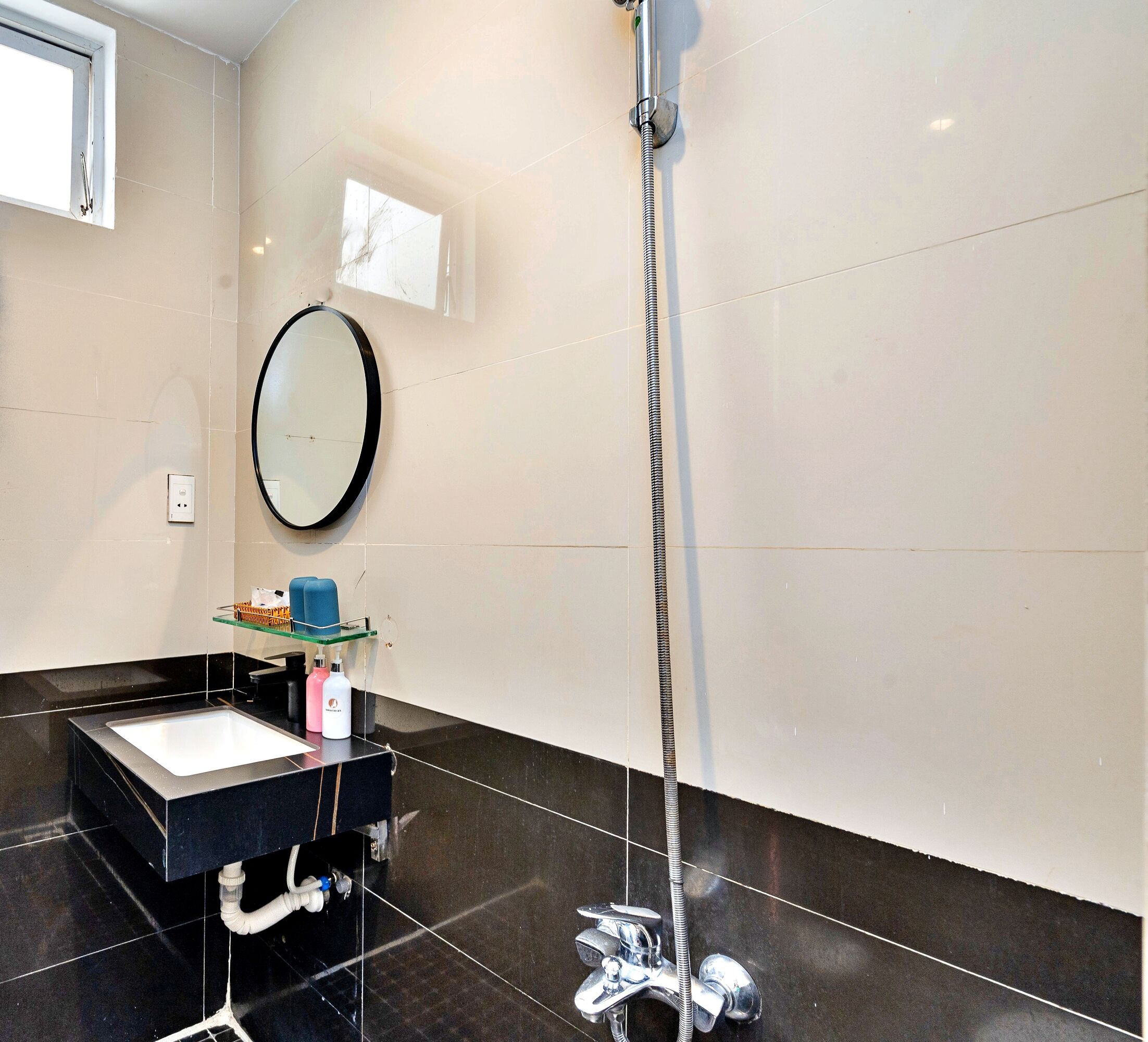 A modern bathroom with a black sink, a mirror, and a handheld showerhead.