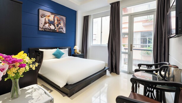 A modern hotel room with a large bed, a desk with a kettle, and a view of the outside. - Nicecy Daily - Bui Vien Walking Street (Ho Chi Minh City)