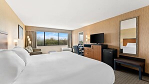 A hotel room with a large bed, a desk with a computer, a TV, and a window with a view of the outdoors. - Quality Hotel Philadelphia Airport (Essington)