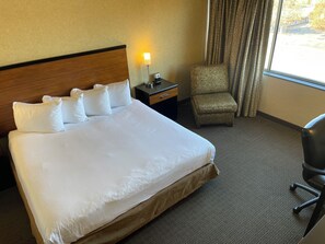 Relax in comfort with a large bed, a bedside table, and a cozy armchair.