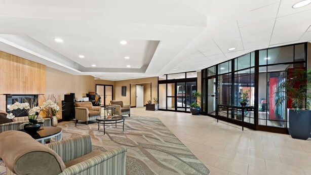 A spacious lobby with a seating area, a reception desk, and a large glass wall offering a view of the outside. - Quality Hotel Philadelphia Airport (Essington)