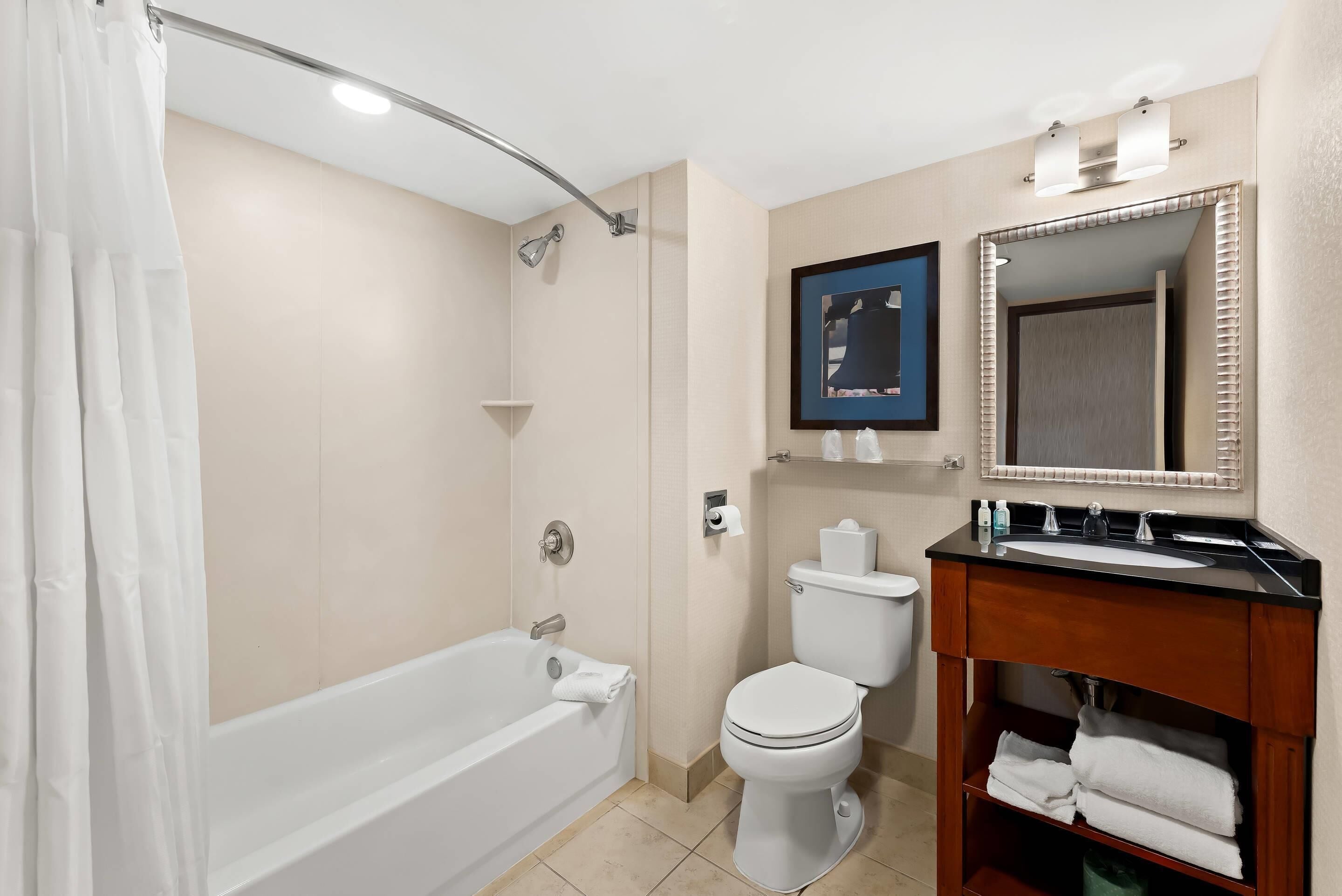 A bathroom with a bathtub, toilet, and vanity with a mirror.