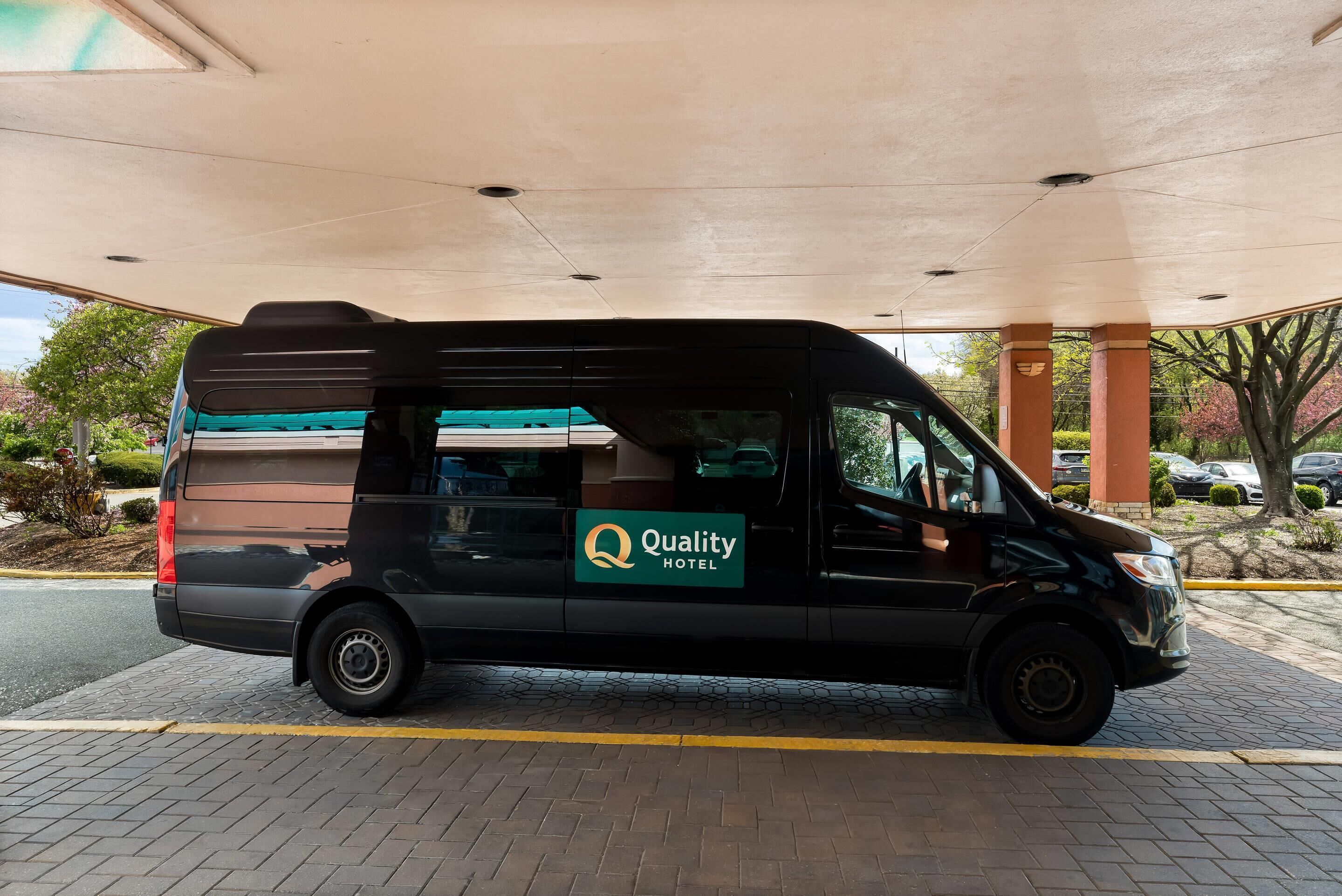 Un furgone nero parcheggiato in un'area coperta, con il logo "Quality Hotel" sul fianco.
