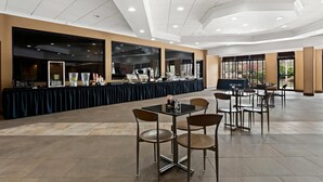 A spacious indoor dining area with a long buffet table, multiple seating arrangements, and large windows providing natural light. - Quality Hotel Philadelphia Airport (Essington)
