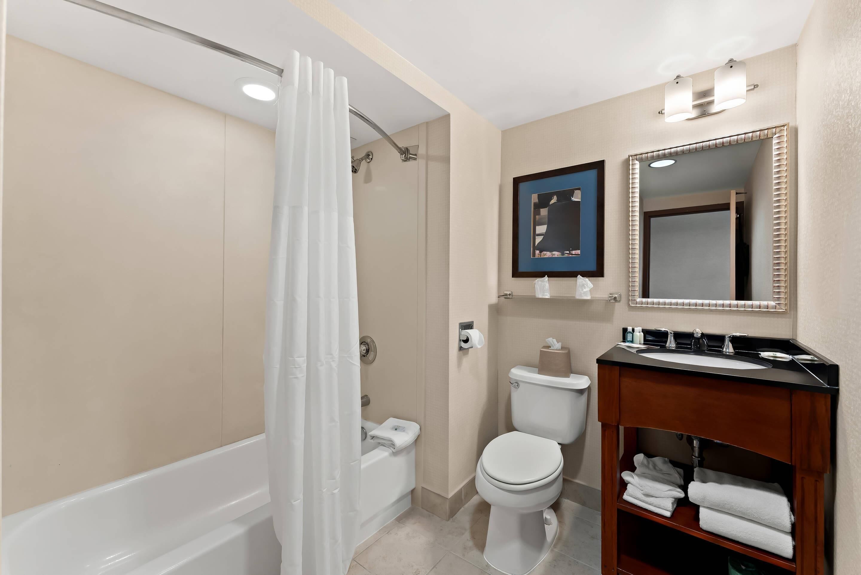 A bathroom with a bathtub, toilet, and vanity with a mirror.