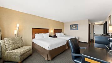 A hotel room with two beds, a desk, a chair, and a sofa.