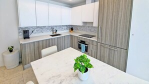 A modern kitchen with white cabinets, a marble countertop, and a built-in oven. - Brand New Apartment in Brickell with free parking-CS65 (Miami)