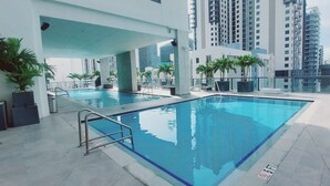 A rooftop pool with clear blue water, surrounded by modern buildings and palm trees. - Brand New Apartment in Brickell with free parking-CS65 (Miami)
