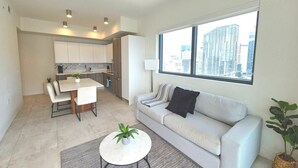 A modern apartment with a dining area, a sofa, and a large window with a city view. - Brand New Apartment in Brickell with free parking-CS65 (Miami)