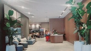 A spacious lobby with a reception desk, seating area, and large potted plants. - Brand New Apartment in Brickell with free parking-CS65 (Miami)