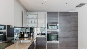 A modern kitchen with built-in appliances, a large island, and a view of the outdoors. - Chic St. John's Wood 1BR w/ Elevator, Fully Furnished, by Blueground (London)