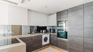 A modern kitchen with a built-in washing machine, a coffee maker, and a toaster. - Chic St. John's Wood 1BR w/ Elevator, Fully Furnished, by Blueground (London)