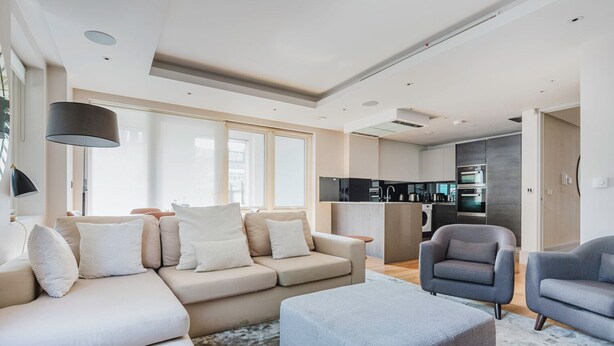A modern living room with a sofa, two armchairs, a coffee table, and a kitchen area with appliances. - Chic St. John's Wood 1BR w/ Elevator, Fully Furnished, by Blueground (London)