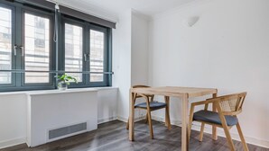 Een kamer met een raam, een radiator, een tafel en twee stoelen.