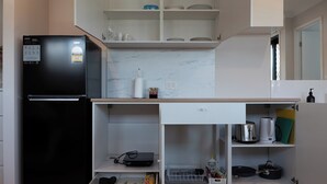 A compact kitchen with a black refrigerator, white cabinets, and a marble backsplash. - New 1 bedroom micro apartment for 2 (Wynnum)