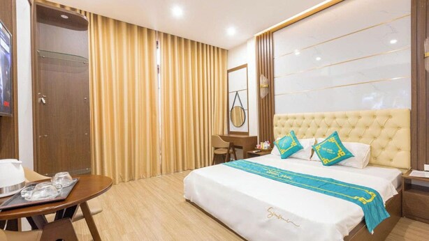 A hotel room with a large bed, a desk, a chair, and a TV. - Hai Yen Hotel - 109 Tran Duy Hung (Hanoi)