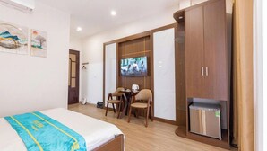 A hotel room with a bed, a desk with two chairs, a television, and a wardrobe. - Hai Yen Hotel - 109 Tran Duy Hung (Hanoi)