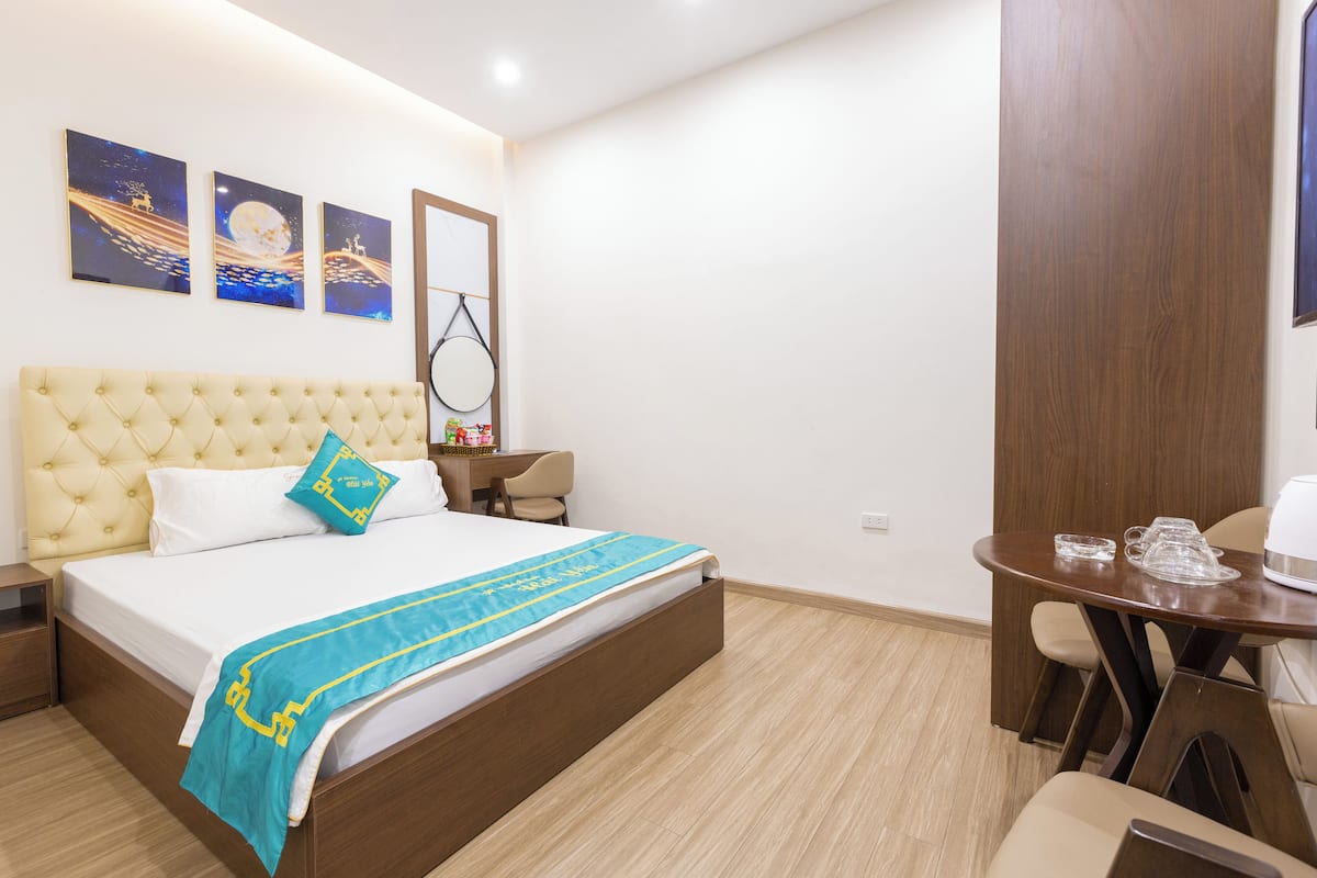 A hotel room with a bed, a desk, and a dining table.