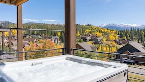 A hot tub with a view of a residential area and mountains in the background.