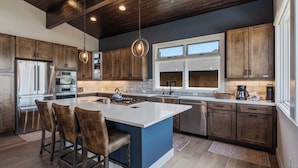 A modern kitchen with wooden cabinets, stainless steel appliances, and a large island with bar stools.
