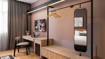 Una habitación de hotel moderna con escritorio, silla y cama con cabecera.