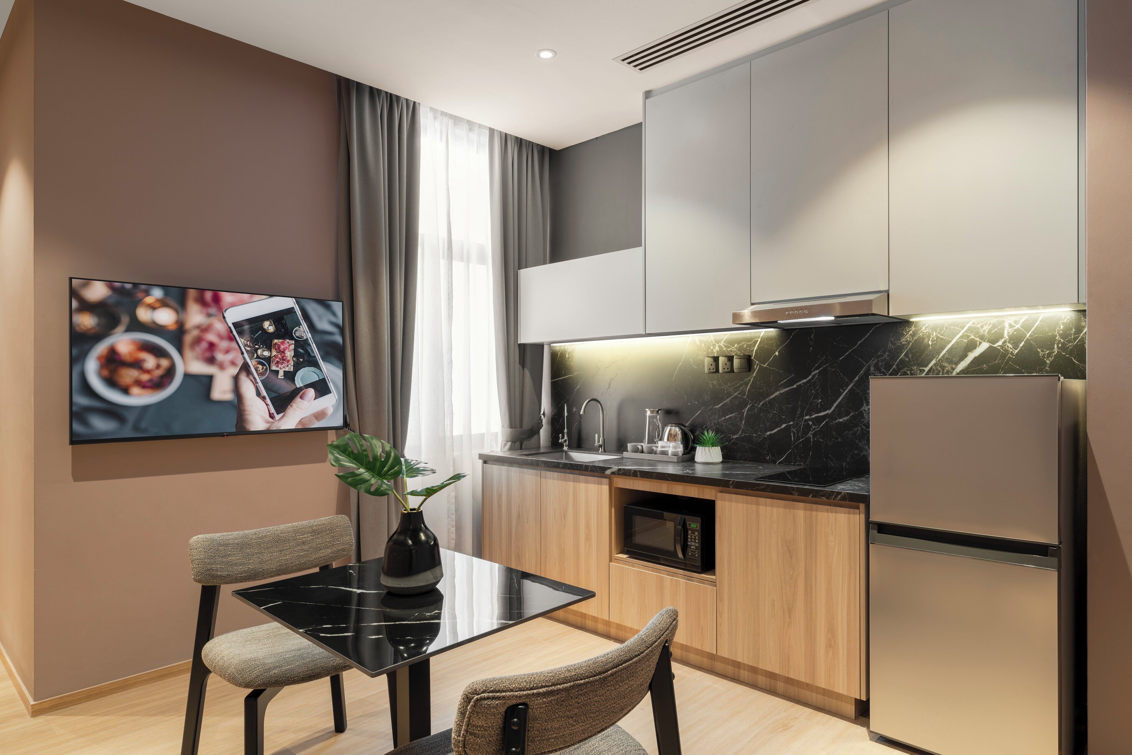 Una cocina moderna con comedor, que incluye un televisor de pantalla plana, una planta y un refrigerador elegante.