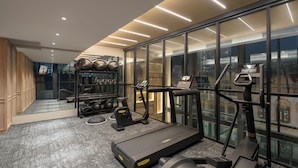 Ein modernes Fitnessstudio mit Laufband, Crosstrainer und Kraftgeräten.