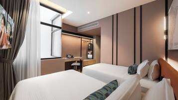 Habitación de hotel con dos camas, un escritorio, un espejo y una ventana con cortinas.
