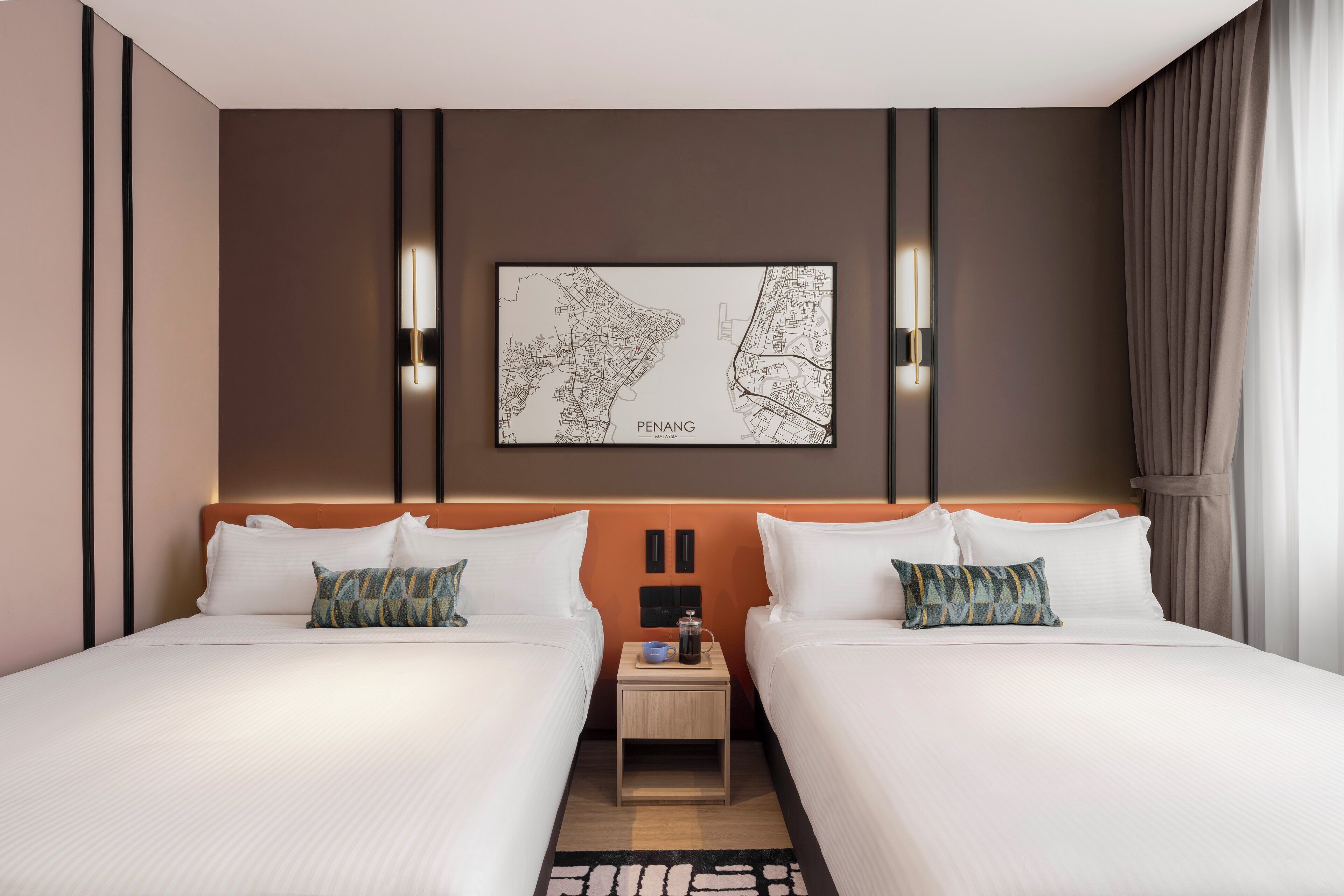 A hotel room with two beds, a nightstand with a coffee pot, and a framed map on the wall.