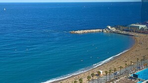 Une scène de plage côtière avec une digue rocheuse, une plage de sable et un espace piscine.