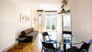 Un salon moderne avec une table en verre, des chaises noires, un canapé marron et un lampadaire.