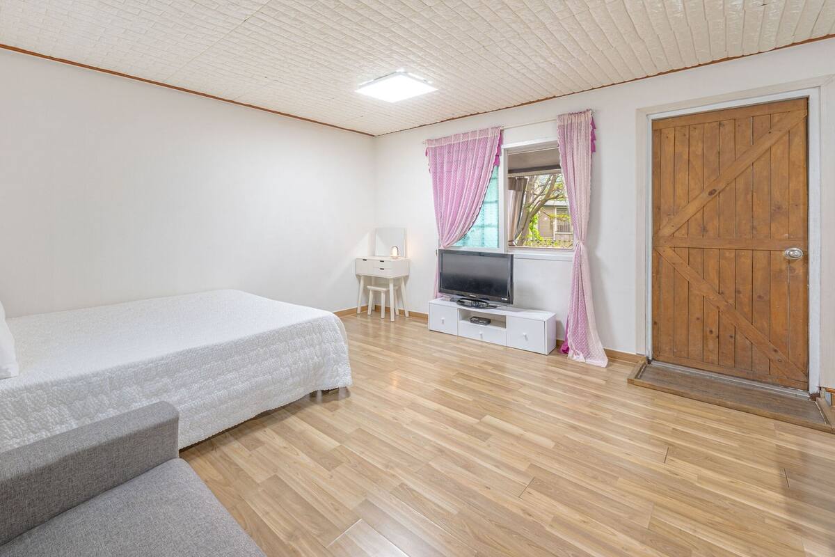 A bedroom with a bed, a TV, a desk, and a wardrobe.