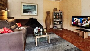 Ett vardagsrum med en soffa, ett soffbord, en bokhylla och en tv.