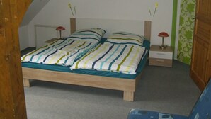 A bedroom with a bed, nightstands, a lamp, a painting, and a patterned wall. - Apartment 'Kelpin' with Private Terrace and Wi-Fi (Möllenbeck)