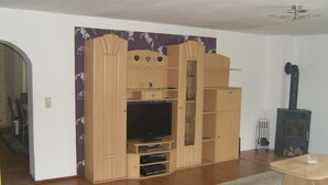 A living room with a wooden entertainment center, a television, a fireplace, and a sofa. - Apartment 'Kelpin' with Private Terrace and Wi-Fi (Möllenbeck)