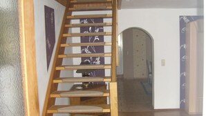 A wooden staircase with a handrail, leading to a landing with a door and a patterned wall. - Apartment 'Kelpin' with Private Terrace and Wi-Fi (Möllenbeck)