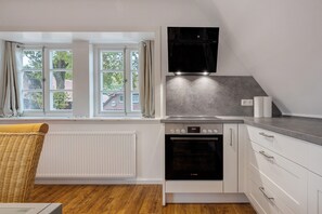 A kitchen with a Bosch oven, a window with curtains, and a view of the outside. - Holiday Home 'Fewo Fachwerk 2' (Hohne)