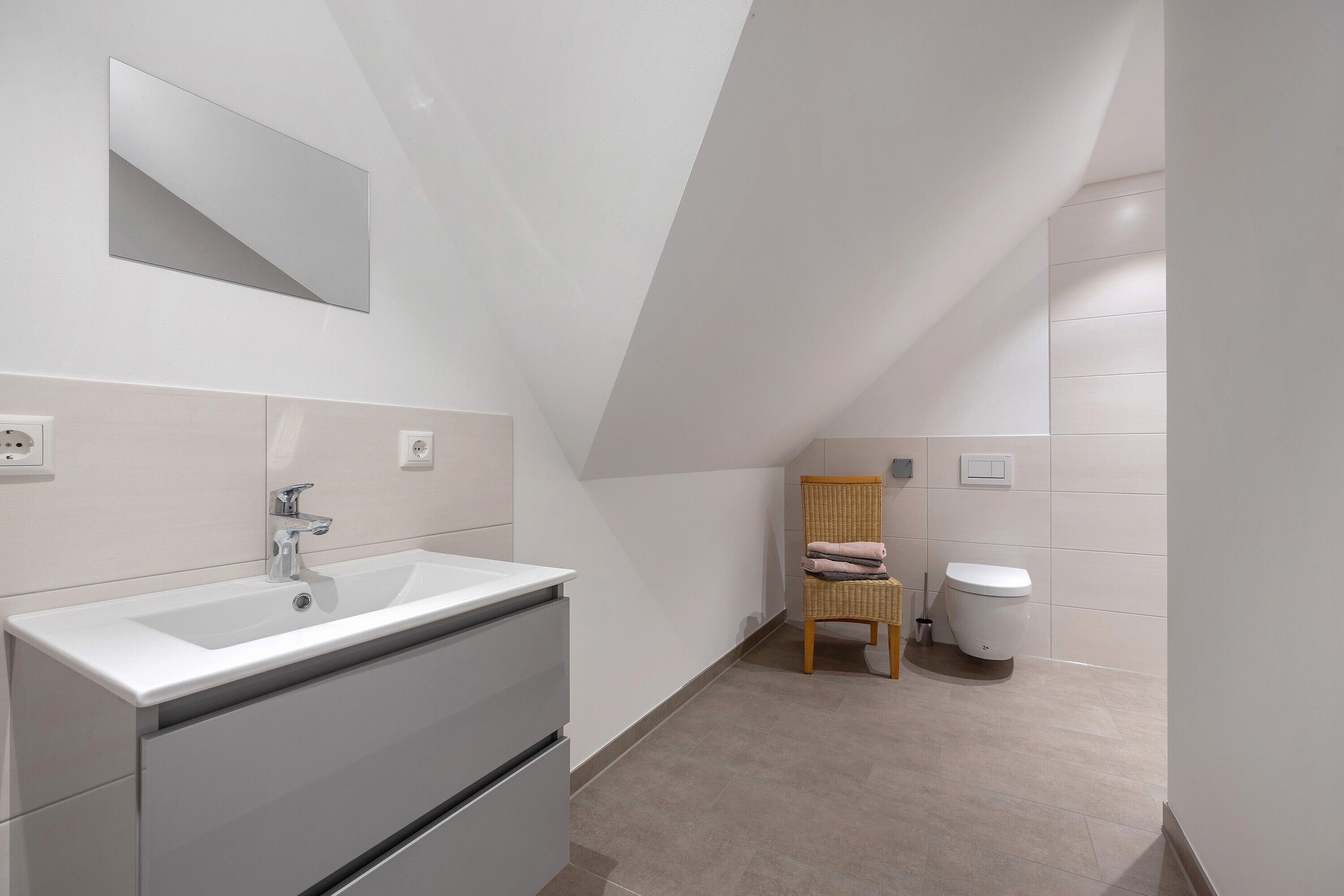 Ein modernes Badezimmer mit Waschbecken, Spiegel und Toilette.
