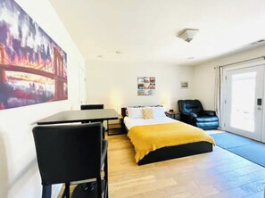 A hotel room with a bed, a desk, a chair, a black leather chair, a yellow throw, and a large painting on the wall. - Big Master Suite with private entry and shared yard in Culver City (Culver City)