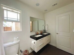 A bathroom with a toilet, two sinks, a mirror, and a white door. - Big Master Suite with private entry and shared yard in Culver City (Culver City)