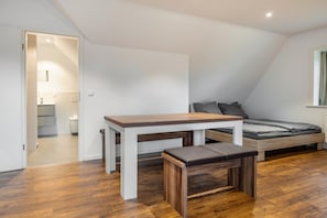 A bedroom with a bed, a table, and a bench.