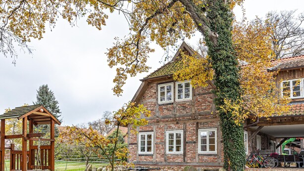 Een traditioneel bakstenen huis met een houten veranda, een schommel en een fiets.