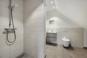 A modern bathroom with a shower, toilet, and sink.