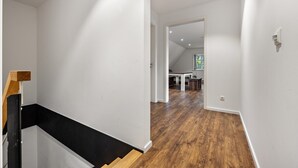 Een modern interieur met een trap, houten vloeren en uitzicht op een eetgedeelte.