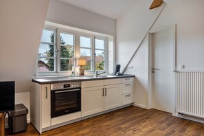 A kitchen with a window, oven, and white cabinetry.